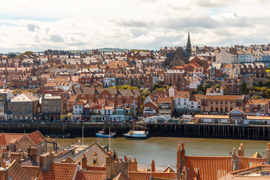 Aerial view of cityscape against cloudy sky on sunny day, Whitby, Yorkshire, UK