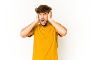Young arab man on white background covering ears with hands trying not to hear too loud sound.