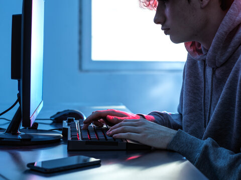 Midsection of teenage boy breaching data from computer on desk
