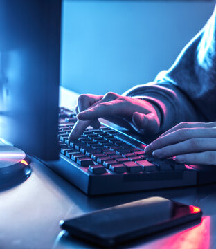 Hands Of Teenage Boy Hacking Computer On Desk