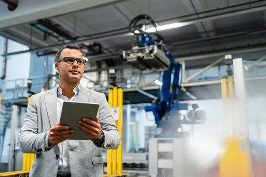 Manager holding digital tablet while looking around in industry
