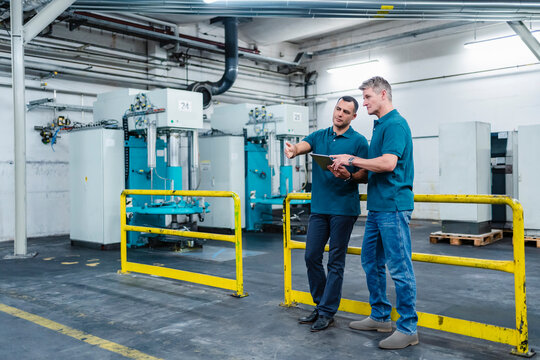 Engineers planing strategy over digital tablet in factory