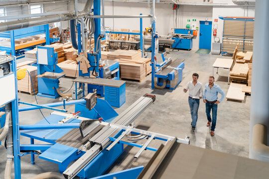 Two carpenters walking and talking in production hall