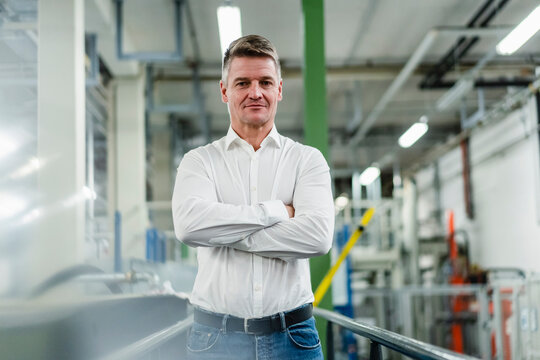 Smiling male entrepreneur with arms crossed in industry