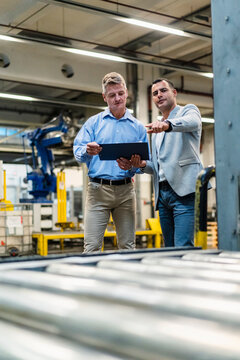 Mature manager looking at document while discussing with supervisor in industry