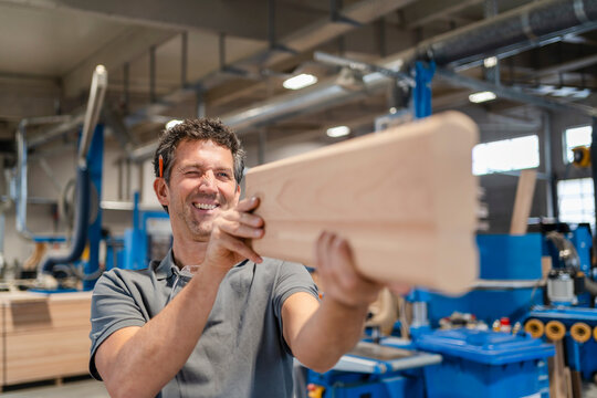 Portrait of carpenter examining plank of wood