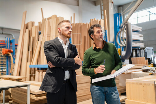 Two&not;&dagger;carpenters&not;&dagger;standing side by side and talking in production hall