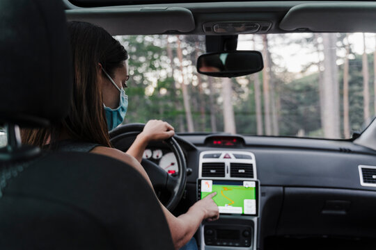Woman wearing face mask using GPS while driving car
