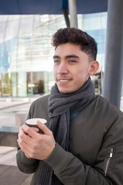 Smiling man day dreaming while holding disposable coffee cup
