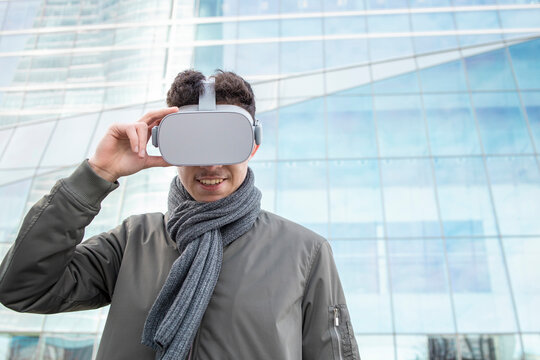 Smiling man using virtual reality simulator against glass building