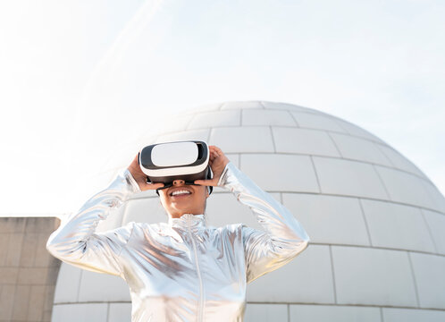 Woman wearing protective suit listening music while standing against igloo