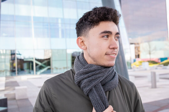 Smiling man wearing scarf looking away against modern building