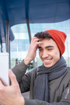 Smiling man with hand in hair taking selfie in city