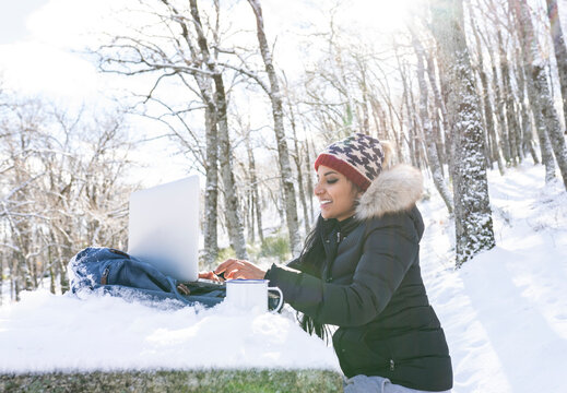 Female entrepreneur working on laptop while sitting on bench during winter