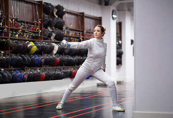 Woman¬†in fencing outfit practicing at gym