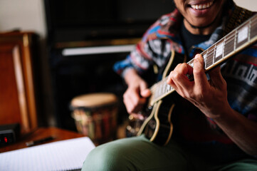 Smiling male musician playing guitar at in living room