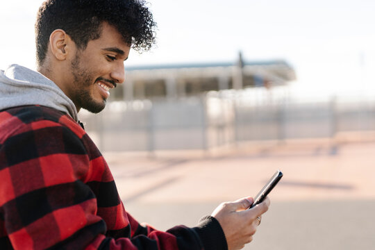 Smiling man using mobile phone while standing outdoors