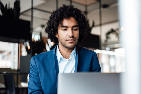 Confident Young Male Professional Using Laptop At Office