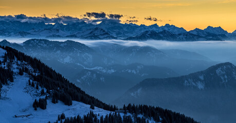 Pre alps panorama mountains at sunrise colored sky foggy morning nature landscapes bavaria germany.
