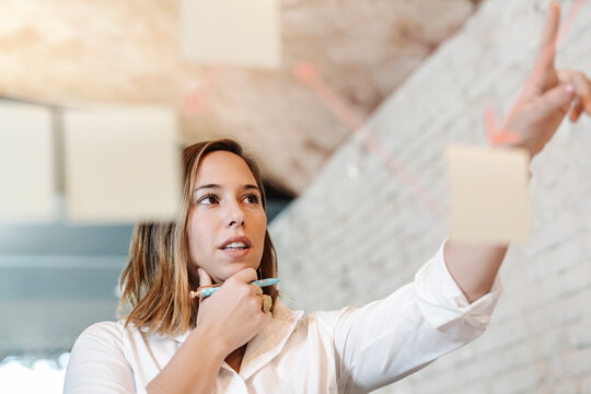 Businesswoman planning over adhesive notes stuck on glass wall in office