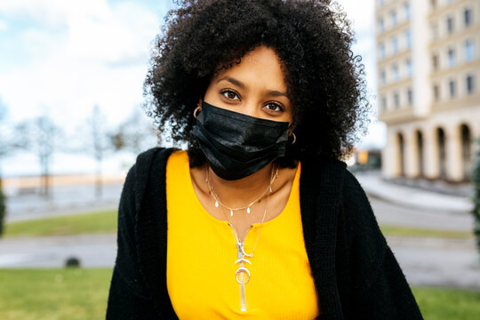 Close-up of young woman with afro hair wearing black face mask