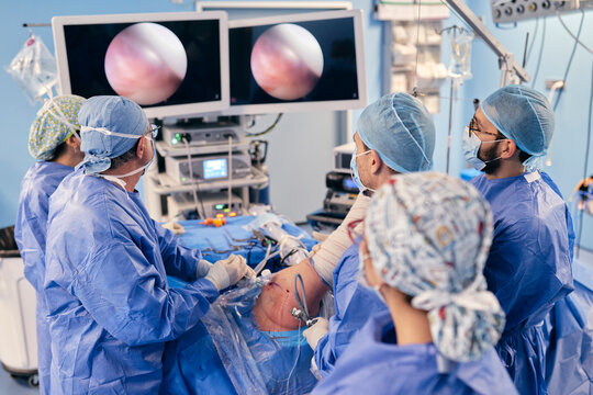 Professionals monitoring surgery on monitoring device while standing in operation COVID-19