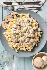 Tagliatelle Italian pasta with forest white champignon mushrooms creamy sauce and chicken or beef meat - homemade food in plate on the table top view close up