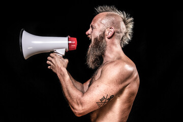 Angry male viking screaming while holding megaphone against black background