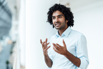 Confident male professional gesturing while standing in office corridor