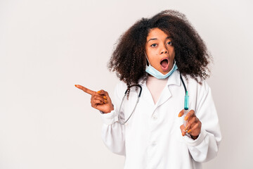 Young african american curly doctor woman holding a syringe pointing to the side