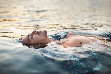 Young man with eyes closed floating in water