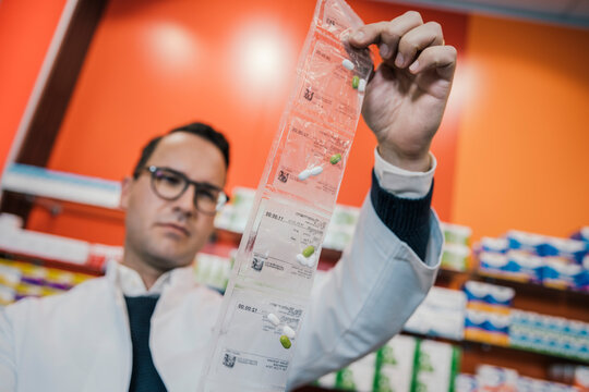 Contemplating pharmacist wearing lab coat while looking at medicines in chemist shop