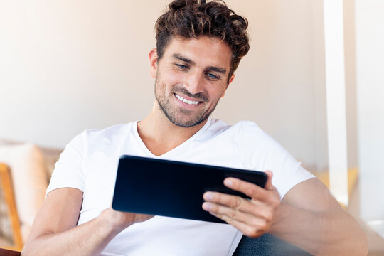 Mid adult man using digital tablet while sitting at home
