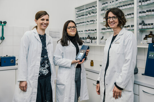 Smiling female pharmacists with NIR spectrometer in chemist store