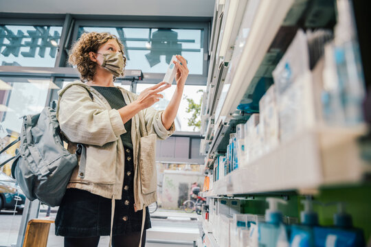 Female customer wearing protective face mask while checking medicine in chemist store