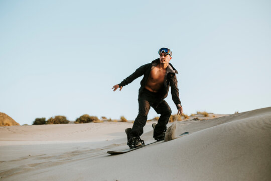 Young man sandboarding in desert at Almeria, Tabernas, Spain - Powered by Adobe