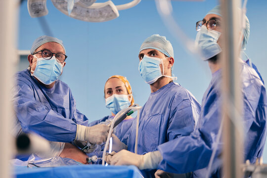 Professionals with endoscope surgical equipment operating surgery while standing in operating room during COVID-19