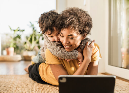 Smiling mother with son using digital tablet while lying at home
