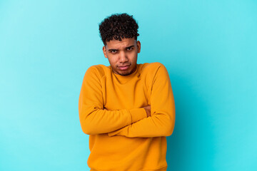 Young african american curly man isolated on blue frowning face in displeasure, keeps arms folded.