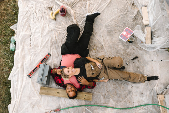 High angle view of smiling woman resting on partner after renovating during summer