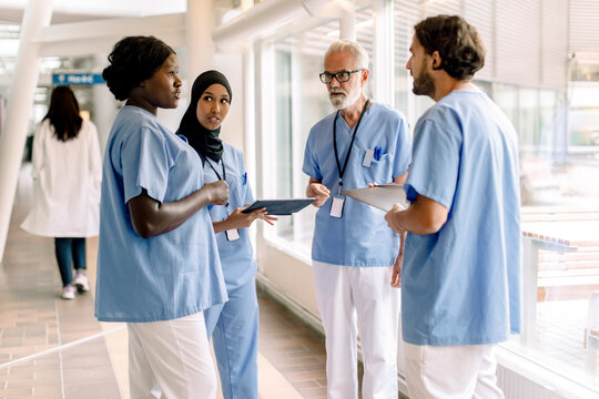 Confident male and female nurses talking in hospital corridor