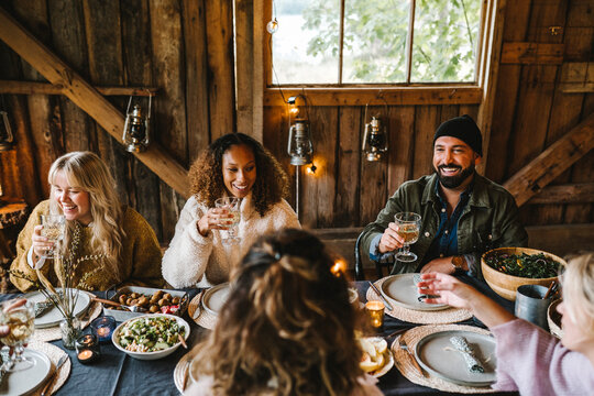 Smiling male and female friends enjoying drinks during social gathering
