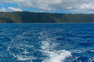 Ocean wake in blue water with view to Hamilton Island