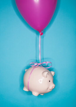 Studio shot of piggy bank lifted by balloon