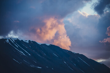 Atmospheric minimal mountain scenery with lilac dawn sky. Scenic minimalist landscape with purple sunset in mountains. Beautiful sunrise in mountains in pastel tones. Rocky mountain in dawn cloudy sky
