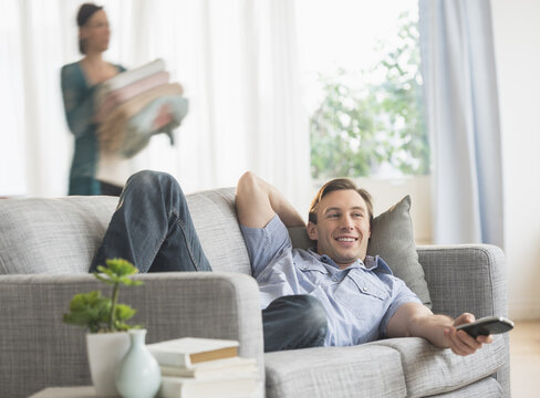 Man lying on sofa watching tv