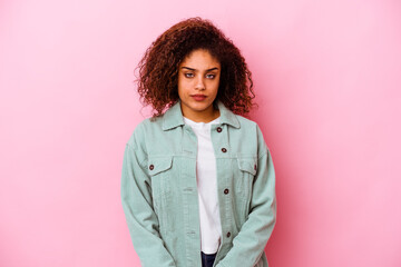 Young african american woman isolated on pink background sad, serious face, feeling miserable and...