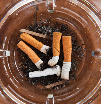 Close up of cigarette butts in glass ashtray
