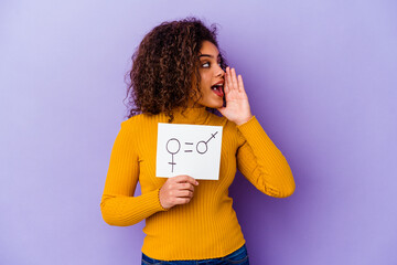 Young African American woman holding a gender equality placard isolated on purple background shouting and holding palm near opened mouth.