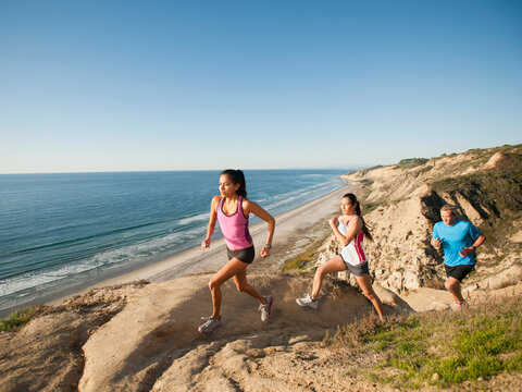 USA, California, San Diego, Three people jogging along sea coast